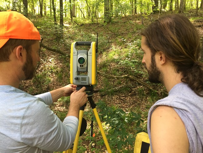 Two men looking at a total station.