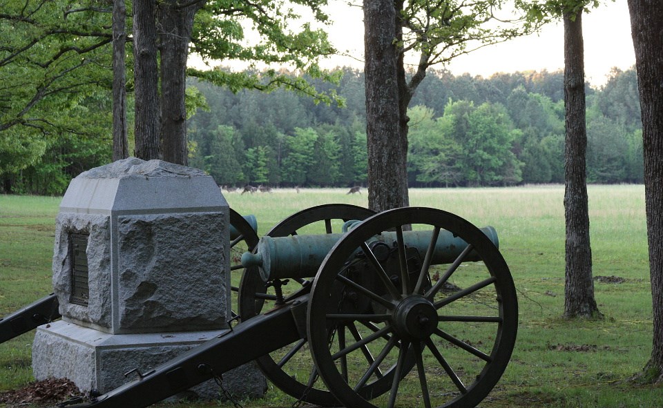 Canon and monument in grassy battlefield