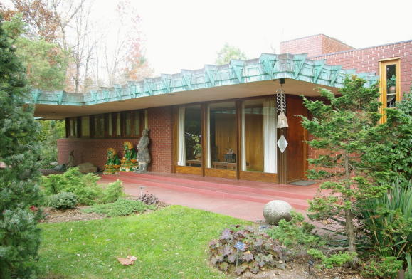 Samara in West Lafayette, Indiana Red brick ranch style home with a green roof.