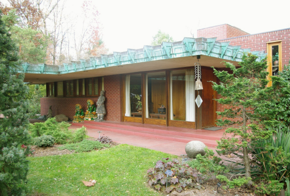 Red brick ranch style home with a green roof.