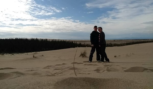 A man and woman stand on sand dunes.