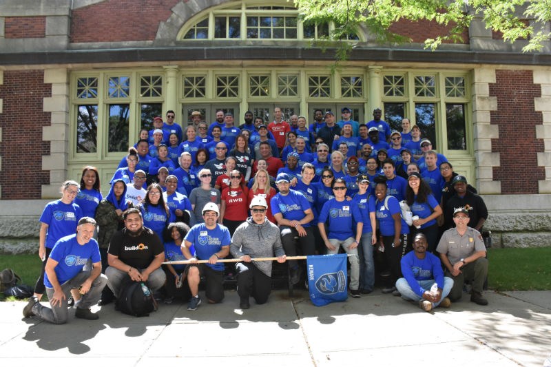 About a hundred people in blue t-shirts standing in rows.