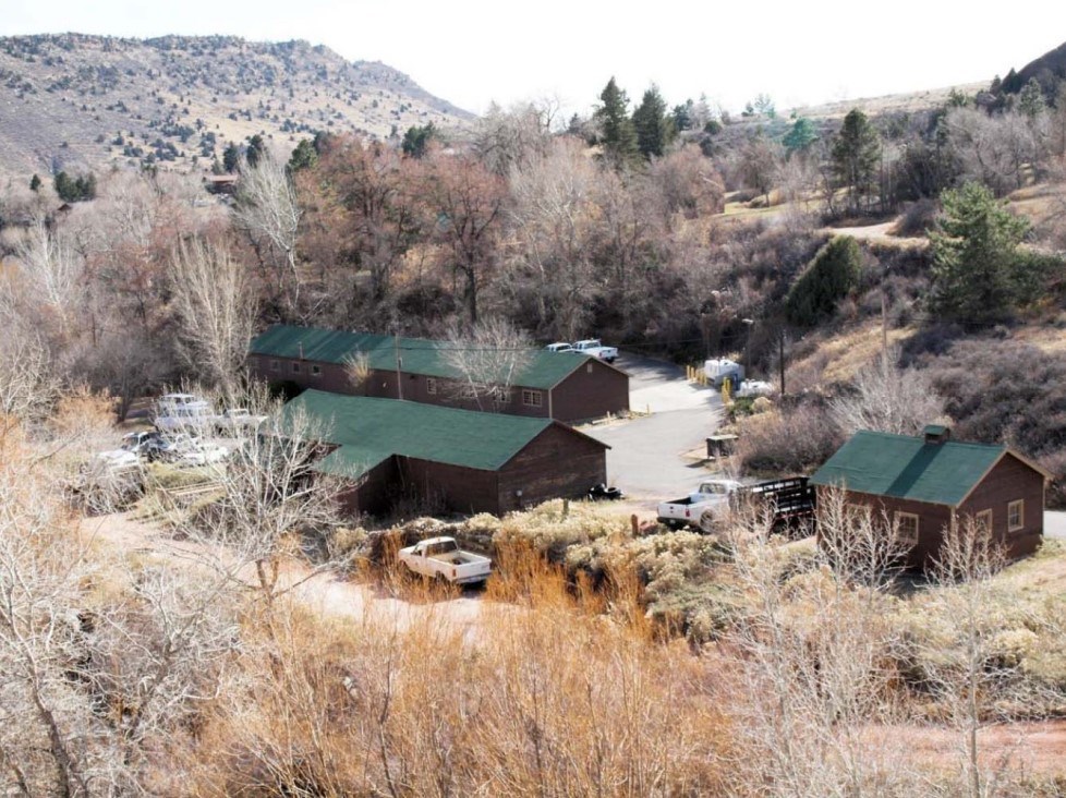 An overhead view of three, wooden cabins with green roofs. They are surrounded by vegetation.