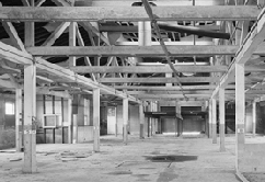 Interior of the stables. B&W photo of heavy timber ceiling framing in the stables.