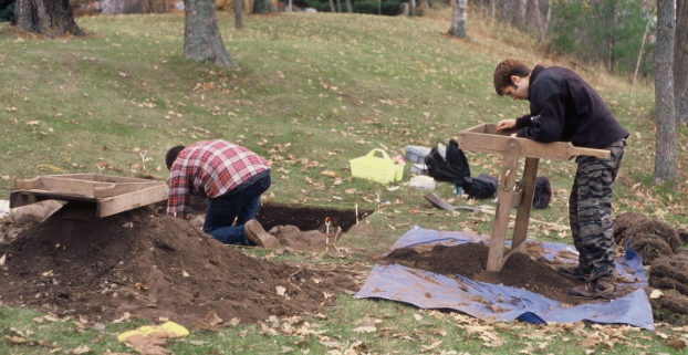 Archaeologists at an NHL Two men digging in the ground.