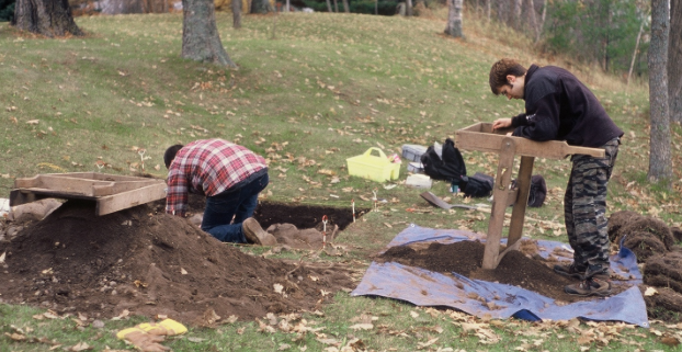 Two men digging in the ground.