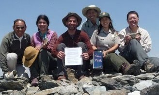 A group of people posing at the top of Sing Peak