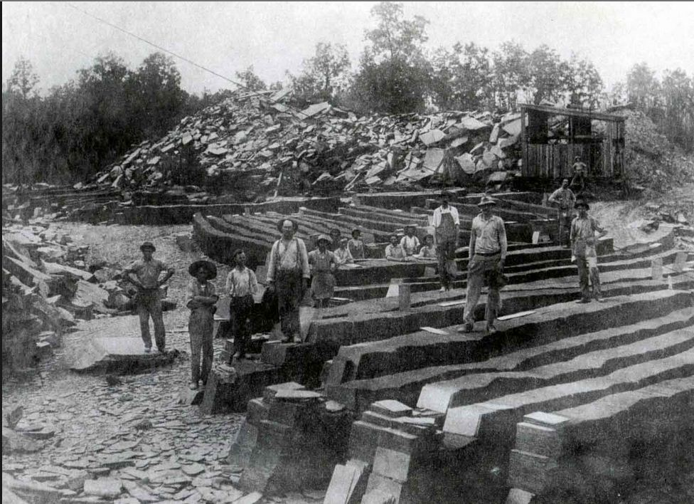 B&W photo of men standing on mined slate rock.