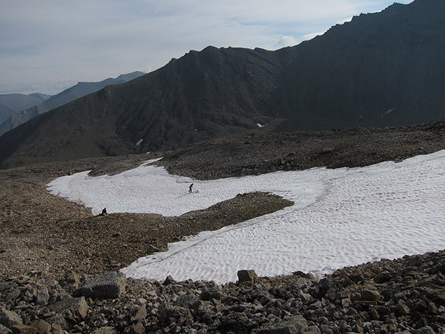 a large patch of snow in a rocky bowl at the top of a mountain