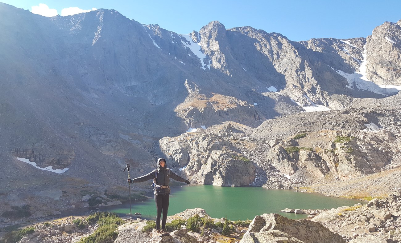 hiker with alpine lake and mountains behind her