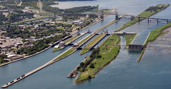 The Soo Locks in Michigan Aerial view of the water canal with green bars of land.