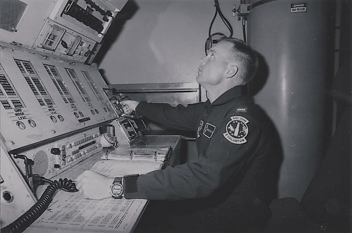 An officer seated in front of a tall electronic control panel.