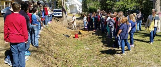 Students flank either side of a ditch dug by enslaved African Americans to enclose the prison camp.