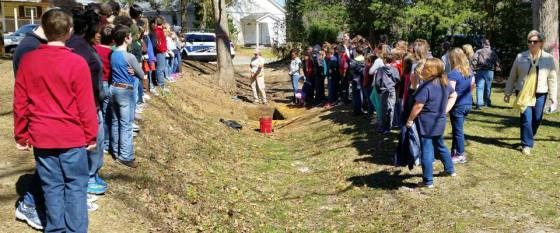 Students flank either side of a ditch dug by enslaved African Americans to enclose the prison camp. Students flank either side of a ditch dug by enslaved African Americans to enclose the prison camp.