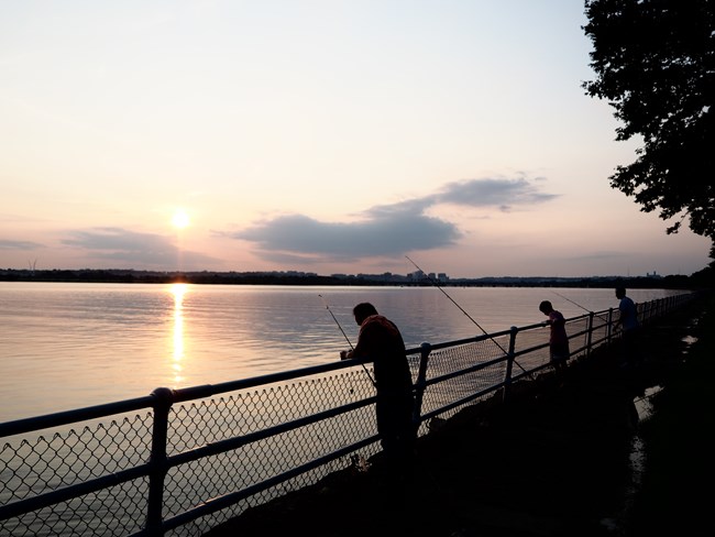 Sunset fishing at Hains Point Fishers in silhouette along the Potomac as the sun begins to set.