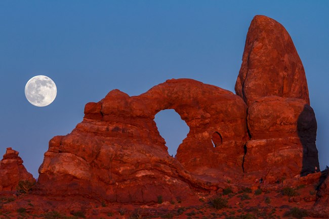 lt= An arch formation at Arches National Park glows under the light of the full moon.