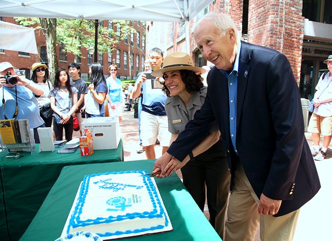 Supt_Celeste_Bernardo_Mayor_William_Samaras_cut_a_white_and_blue_cake. Celebration of Lowell National Historical Parlk