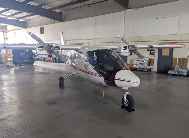 A small, mostly white aircraft parked in a large building.