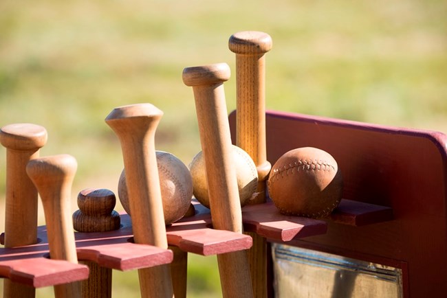 Close up of 1860s-style base ball bats and balls