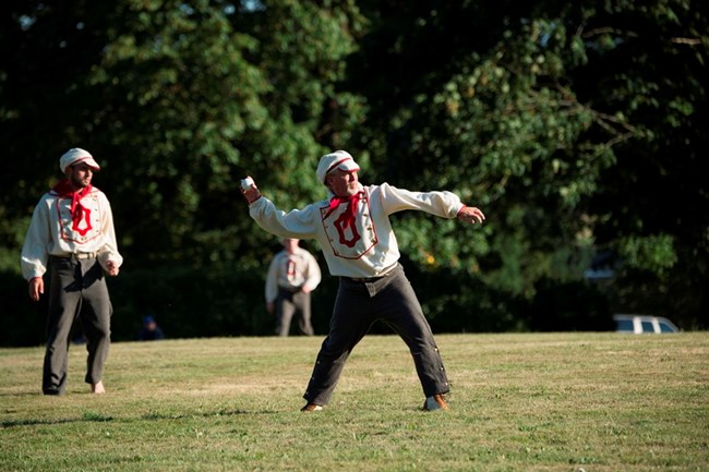 Base ball players wear vintage-style uniforms, white with a large red "O" on front.