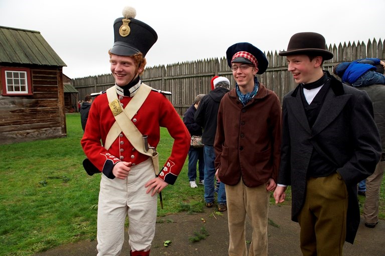 Volunteers at Christmas at Fort Vancouver Three costumed volunteers stand inside the fort. One is wearing a red Royal Marines uniform.