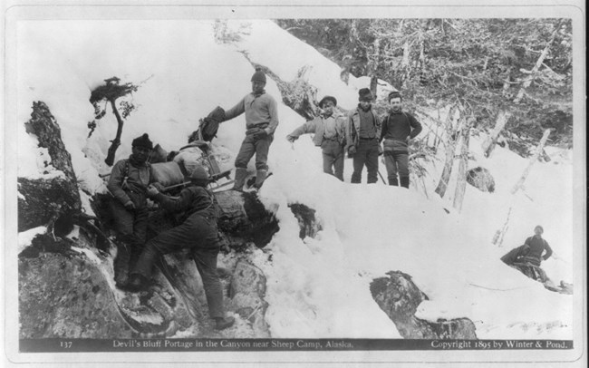 Men trying to haul a sled up a snow covered canyon