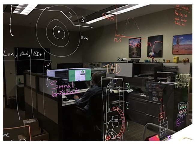 Damon Joyce's reflection is visible on the tech lab blackboard, where ideas develop and evolve.