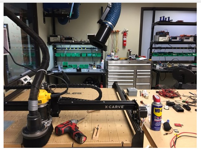 Tech shop view of metal cutting machine, power drill, WD-40 and other tools.