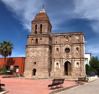 An 18th century church with a bell tower stands in a wide plaza