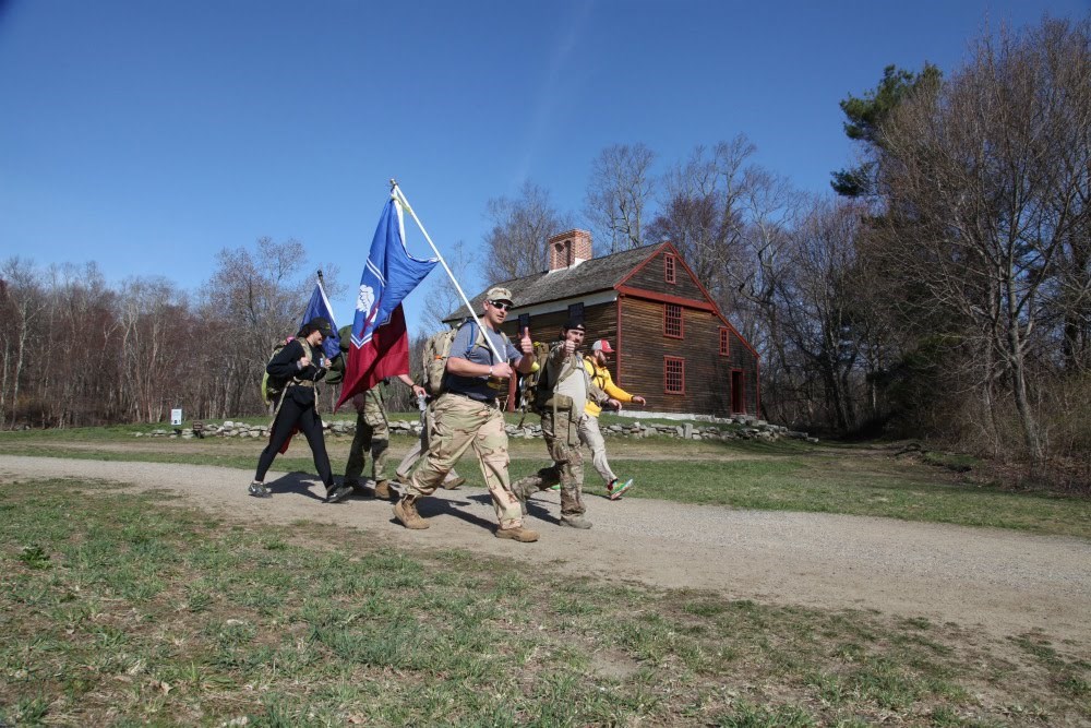 Six National Guard members walking along dirt path.