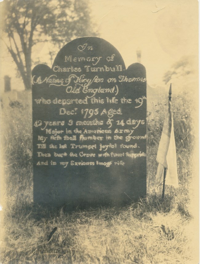 Gravestone, with tri-partite top, and inscription, which has been chalked over for this photo