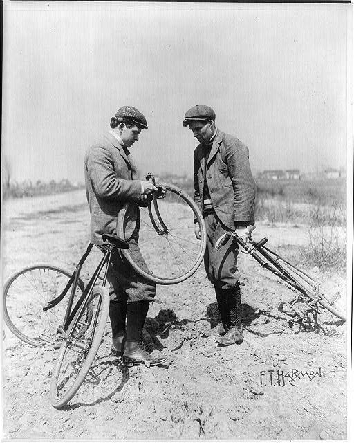 lt= Two men fixing a bike tire