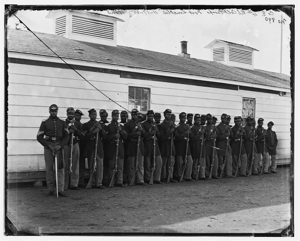 US Colored Troops stand in uniform in front of white building, B&W photo