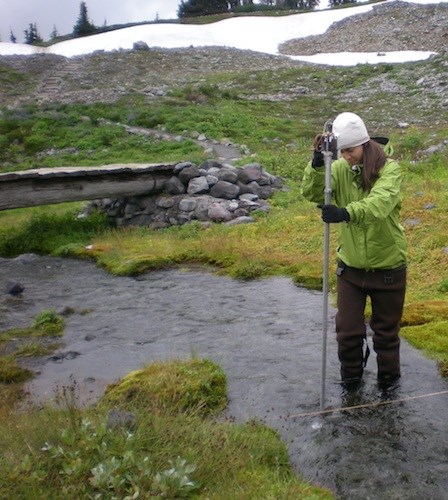 USGS testing below Paradise Warm Springs 2011 A woman wades in a small stream holding a measuring tool into the water.