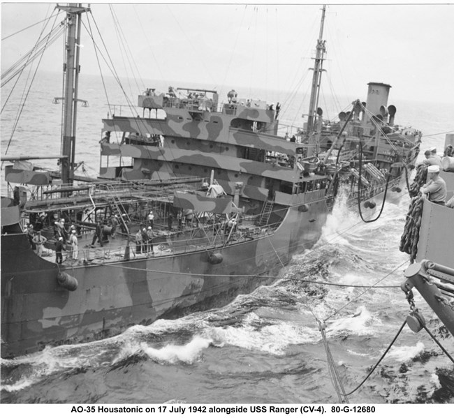 Two ships side by side with cables and fuel lines temporarily connecting them.