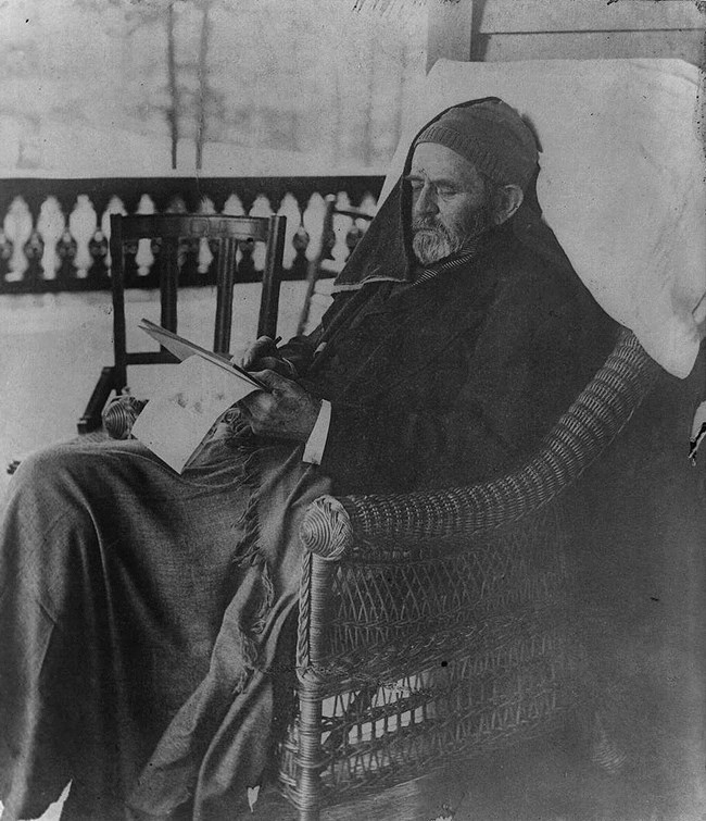 man sitting on a front porch chair and writing