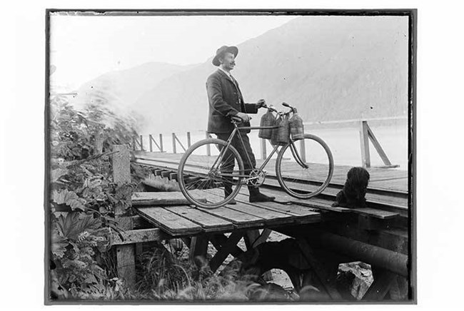 Black and white photo of a man with a bike on a pier