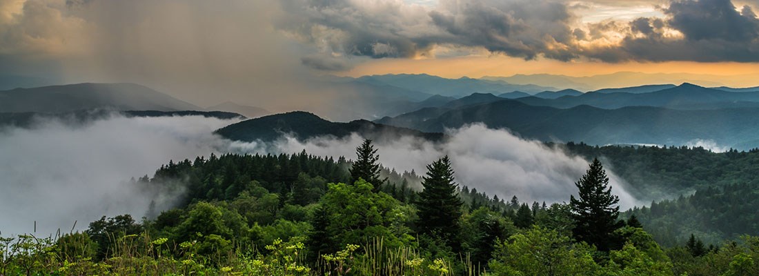 A rain storm veils the mountains at sunset in summer