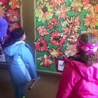 Children look at collages of poinsettia flowers