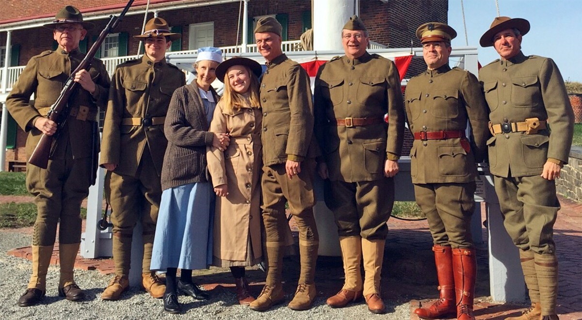 Visitors and staff are dressed in WWI uniforms and period costumes, while posing for a photograph.