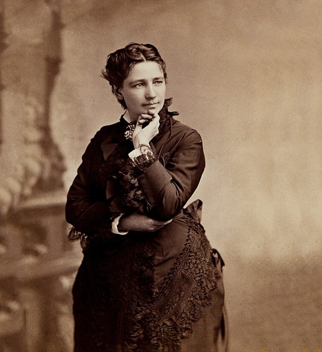 Victoria Woodhull wearing a dress and posing for a picture in the eighteen-sixties.