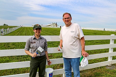 Two park and Gettysburg Foundation staff members help paint white fences at Eisenhower's Farm.