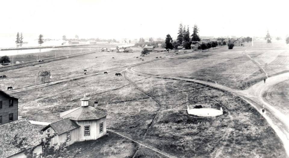 Black and white photo of Vancouver Barracks with open fields and some buildings.