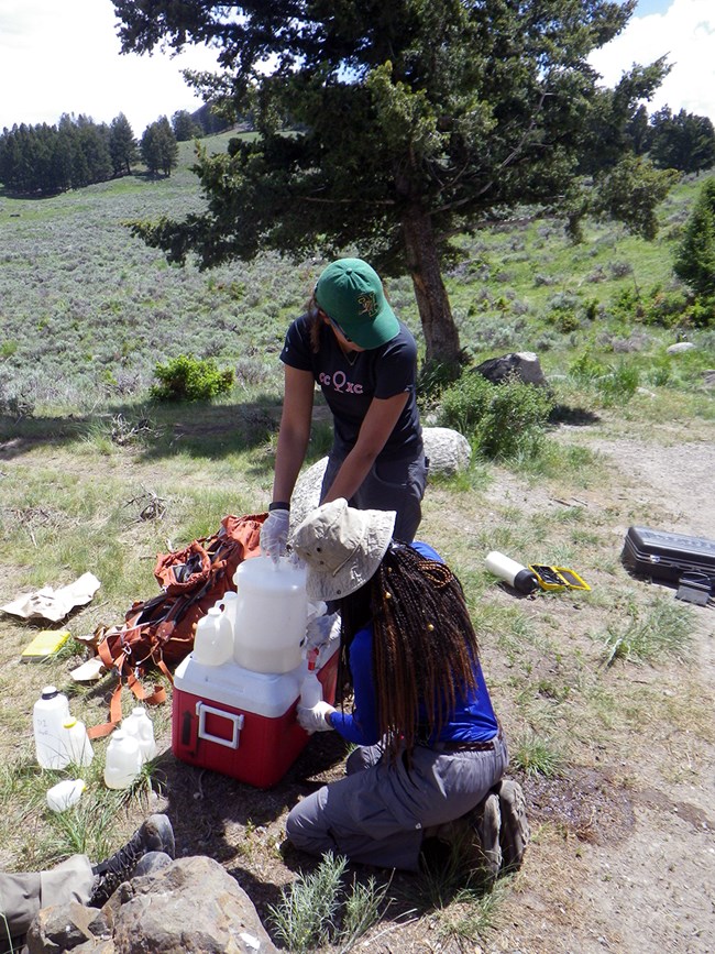 Water quality monitoring two scientists filling small water bottles from a larger bottle