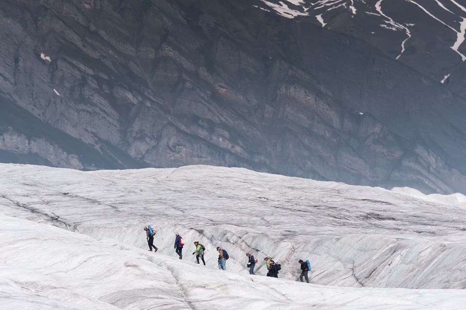 Line of hikers walking on a glacier