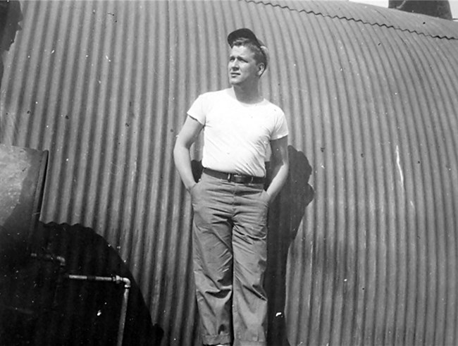 Walter Andersen in 1944 Black and white photo of young man standing in front of rounded, corrugated metal building.