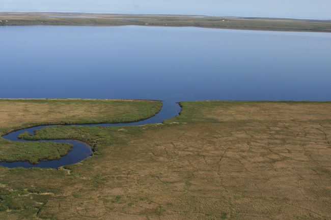 A winding river pours into a large body of water.