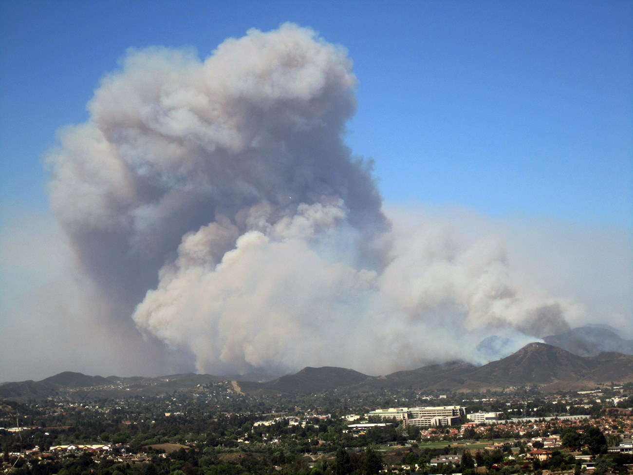 lt= A large plume of smoke towers over the suburban skyline.