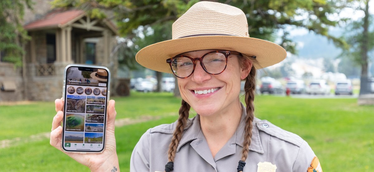 Ranger holding a phone that displays the NPS App