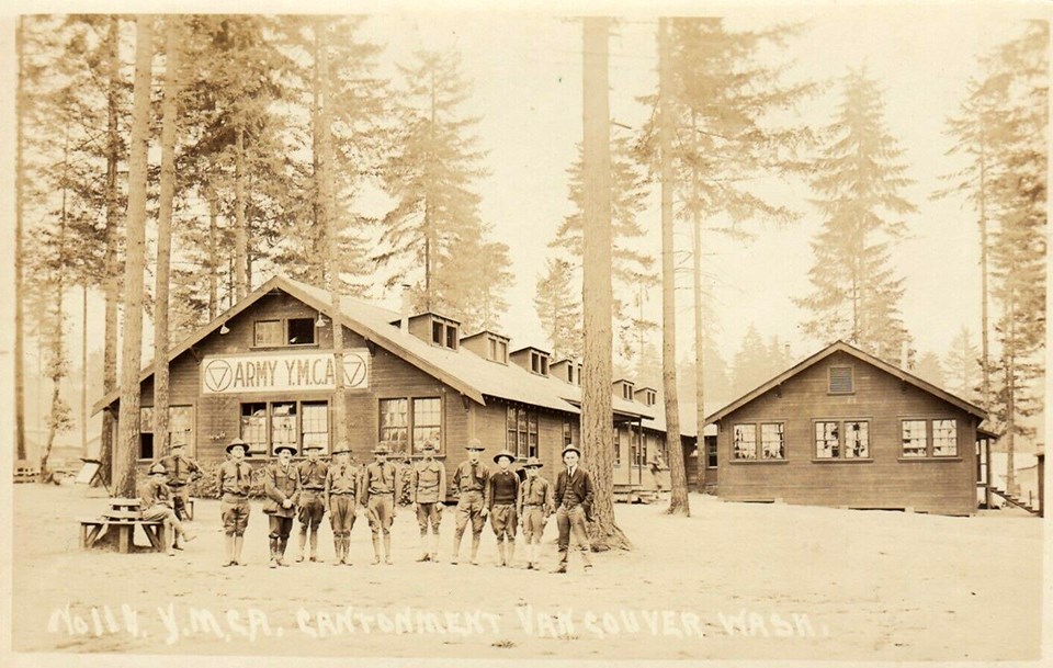 YMCA cantonment - for web Black and white photo of men in military uniforms standing in front of a YMCA building in a forested area.